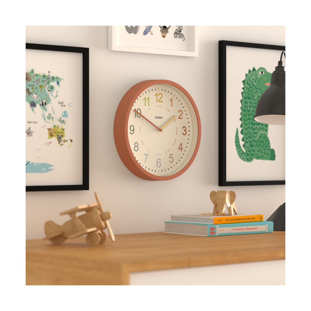 Kids wall clock by Jones Clocks in terracotta orange with a multi-coloured, easy-to-read dial - JDRAG180TO