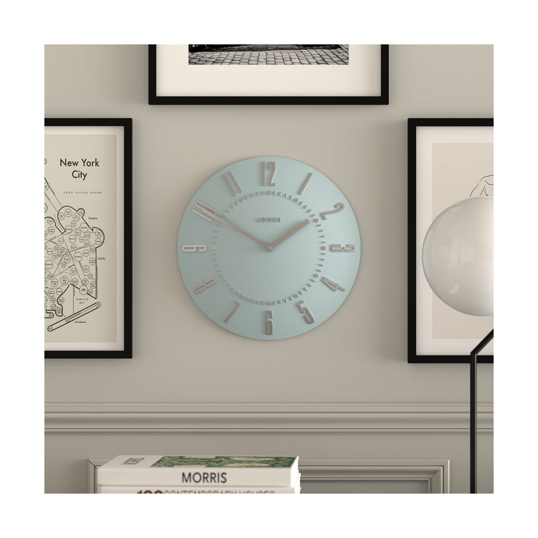 Juke Convex wall clock by Jones Clocks in pale blue with a retro style silver dial, hanging on a living room wall - JJUKECBLS30