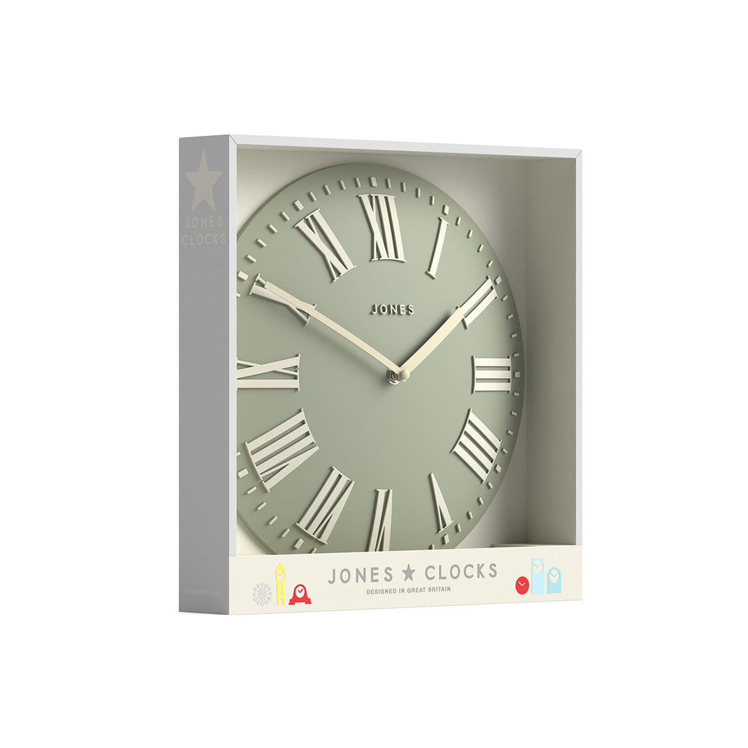 Packaging - Strand convex wall clock by Jones Clocks. Prominent white Roman duals on a sage green background, offering a modern look - JSTRSGLW30