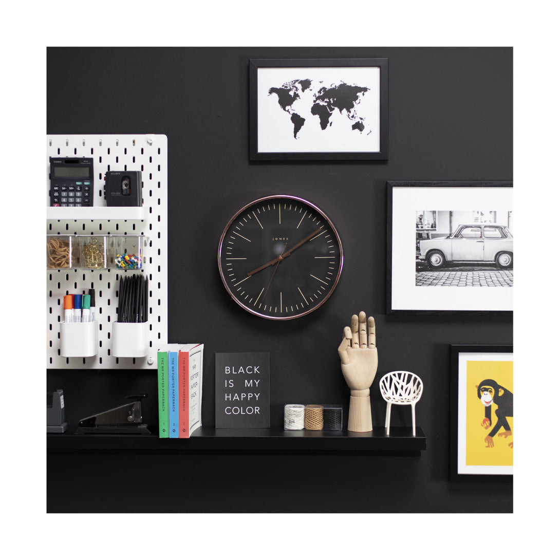 Modern Studio wall clock by Jones Clocks in a copper effect with a reverse black marker dial and copper hands on a black wall