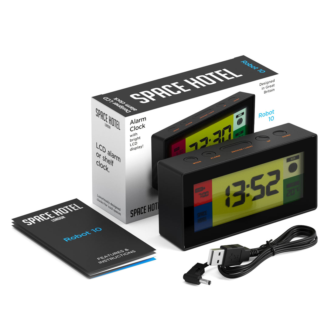 Skewed titled view of the Space Hotel Robot 10 LCD alarm clock in black with multicoloured backlights, with packaging, instructions, and USB Cable